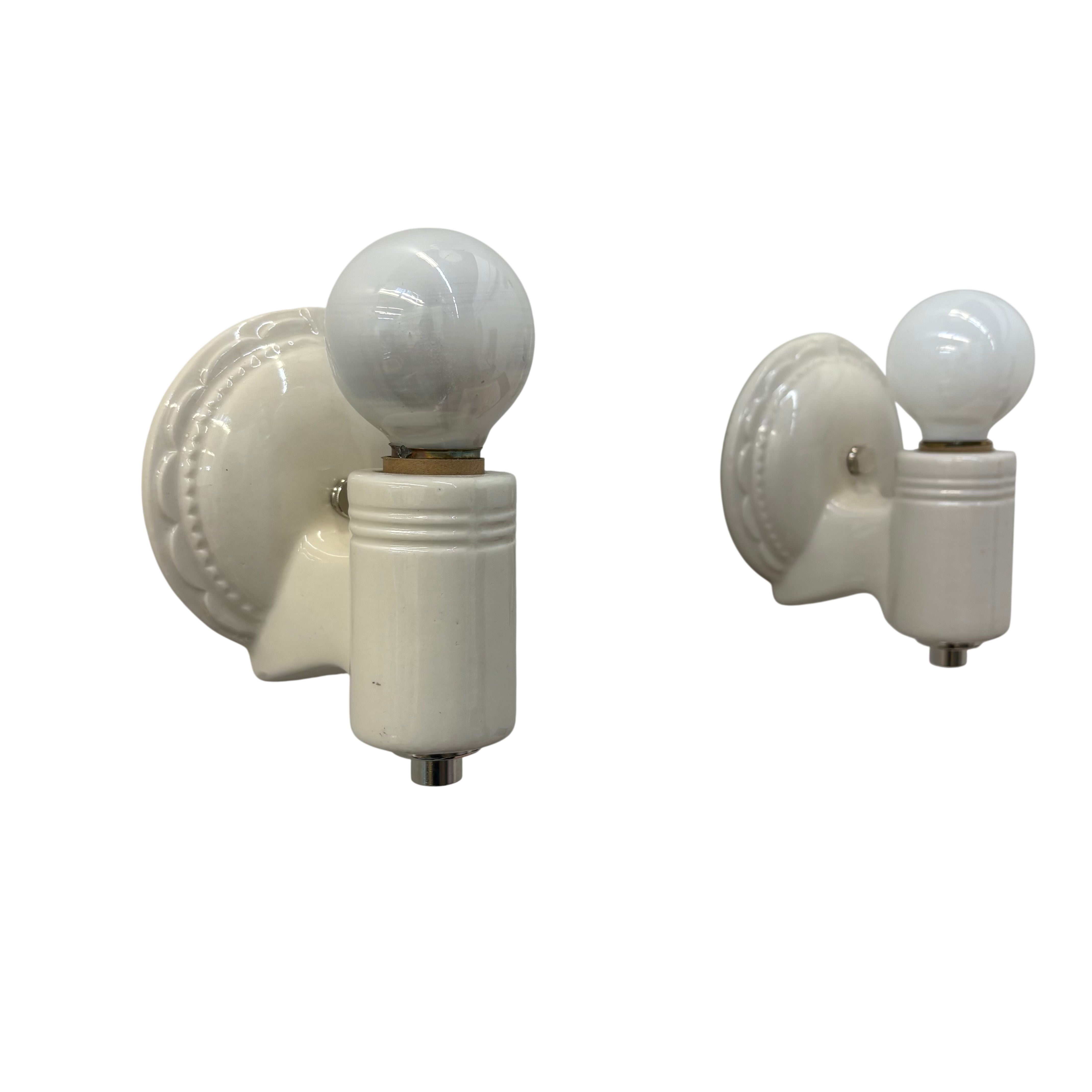Two white wall sconces with globe lights on a white background