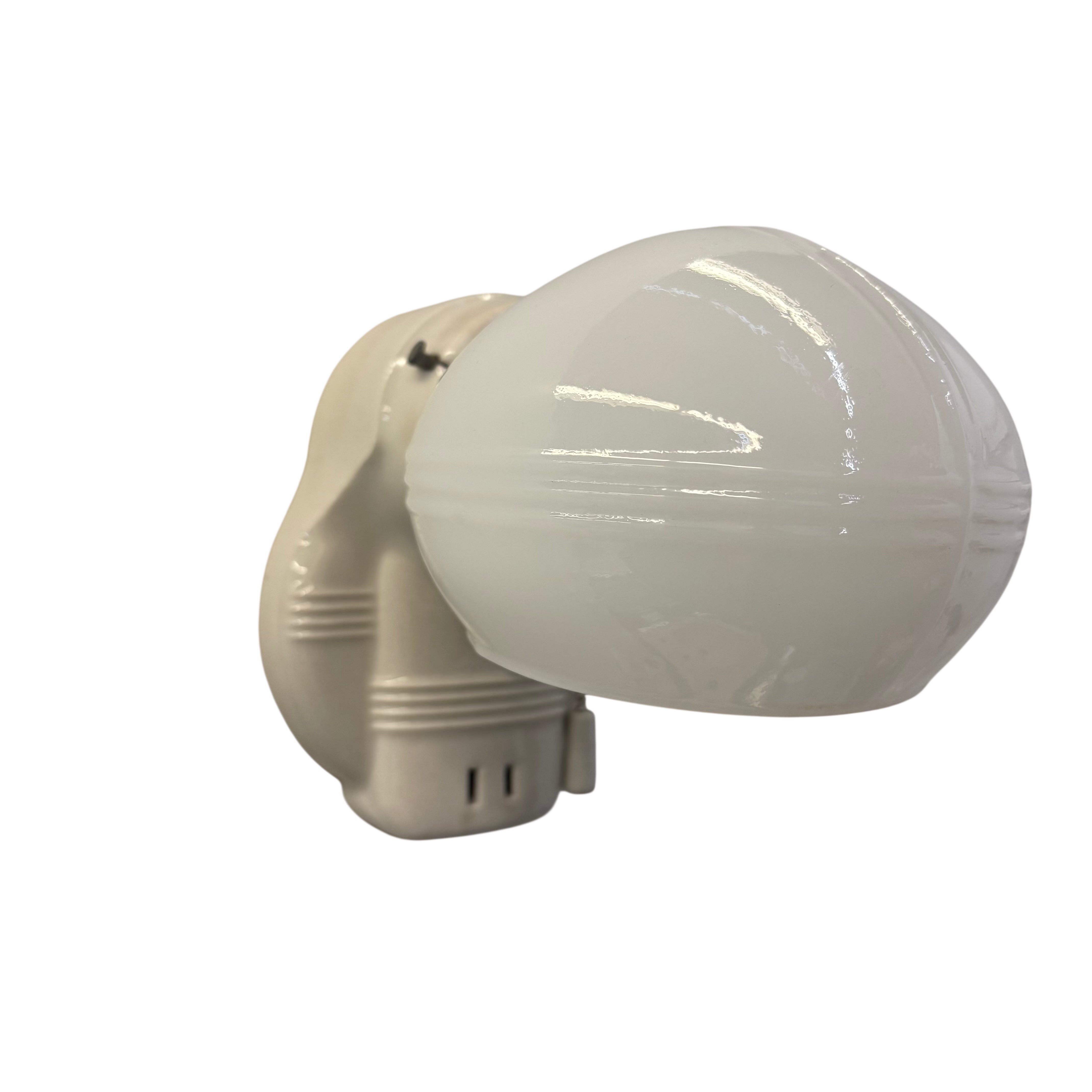 Wall-mounted light fixture with a white glass shade on a white background