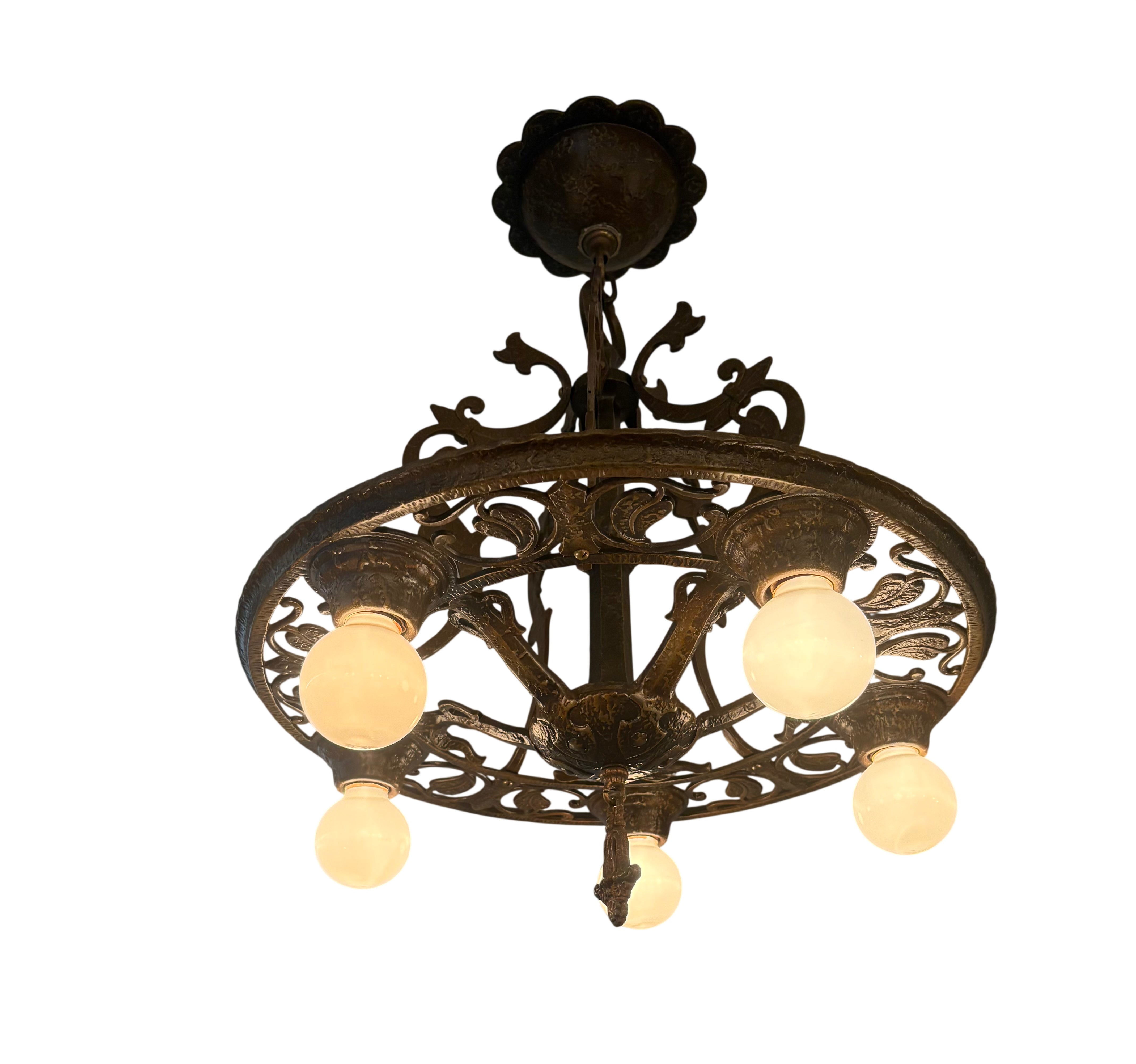 Decorative chandelier with five light bulbs on a ceiling.