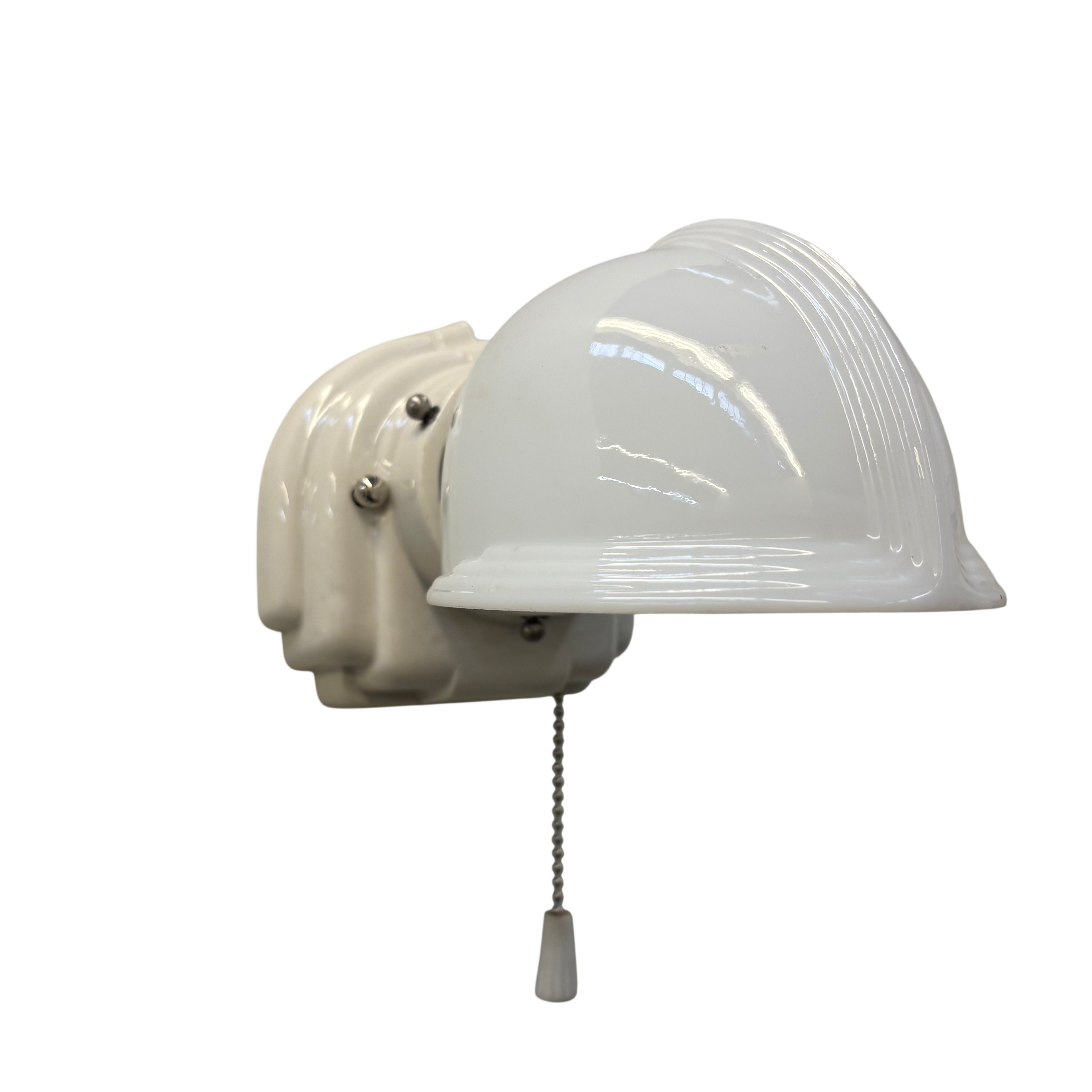 Wall-mounted light fixture with a white shade on a white background
