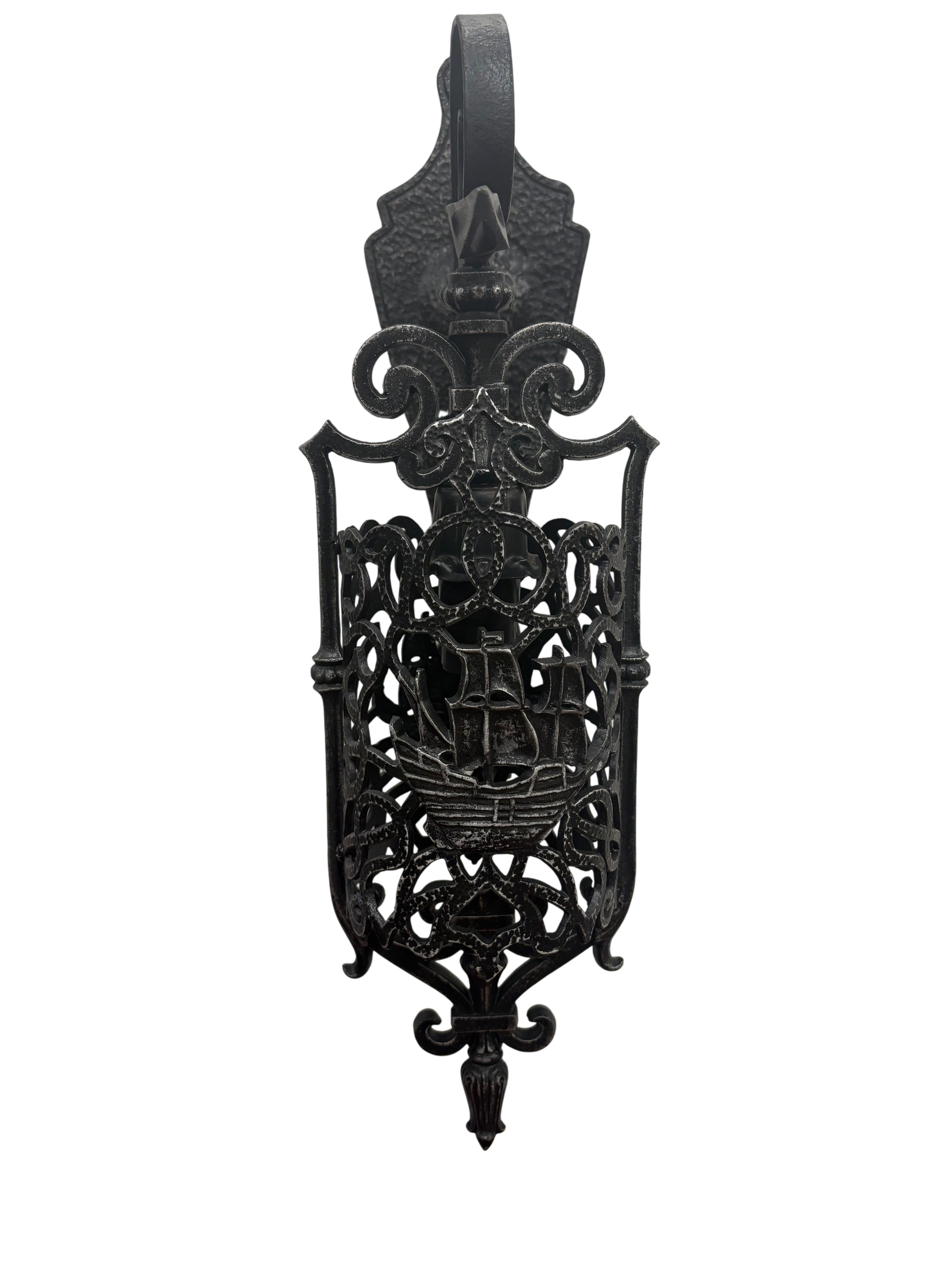 Decorative black metal wall light with intricate designs on a white background