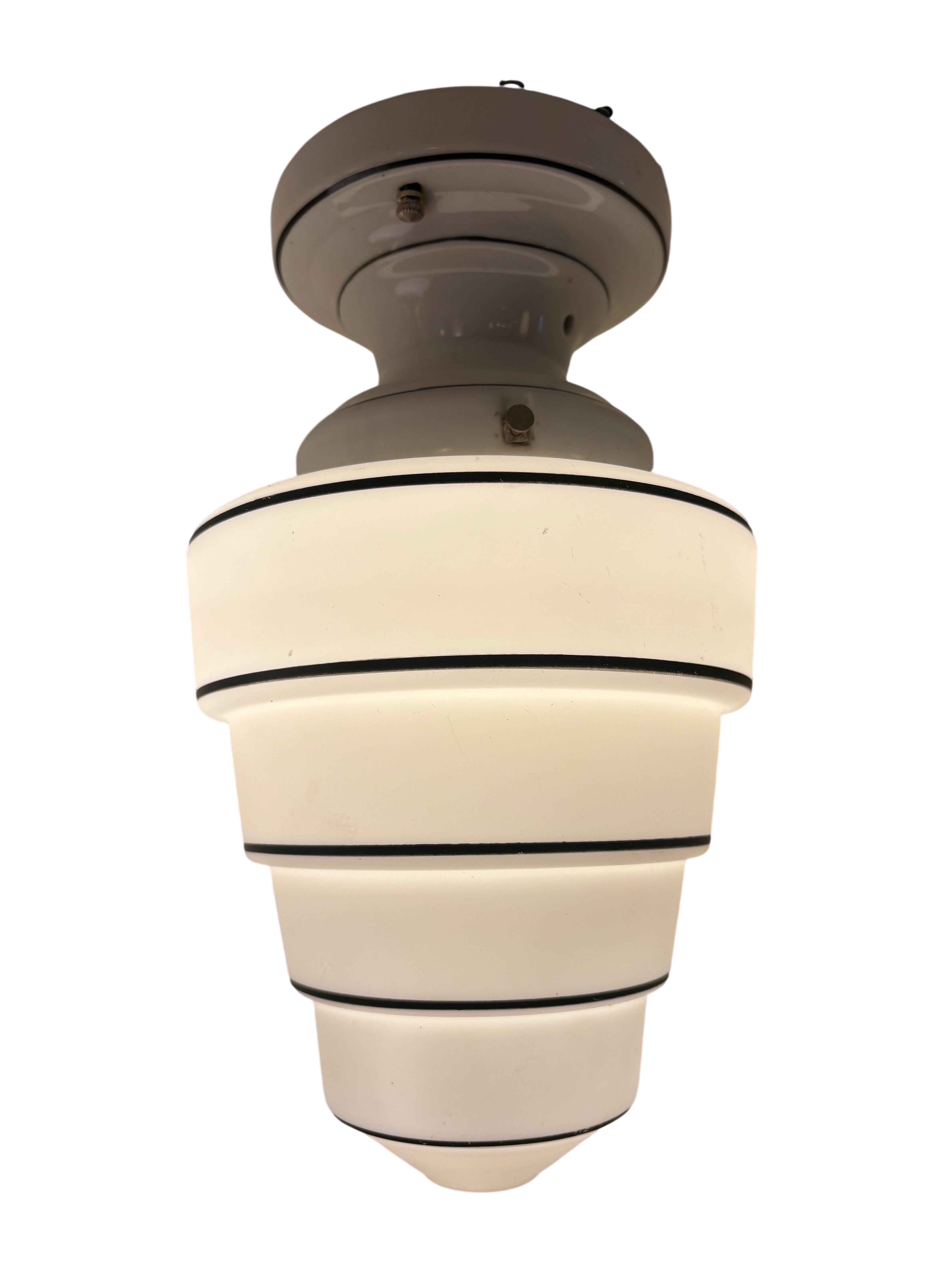 Ceiling light fixture with white shade and black bands on a white background