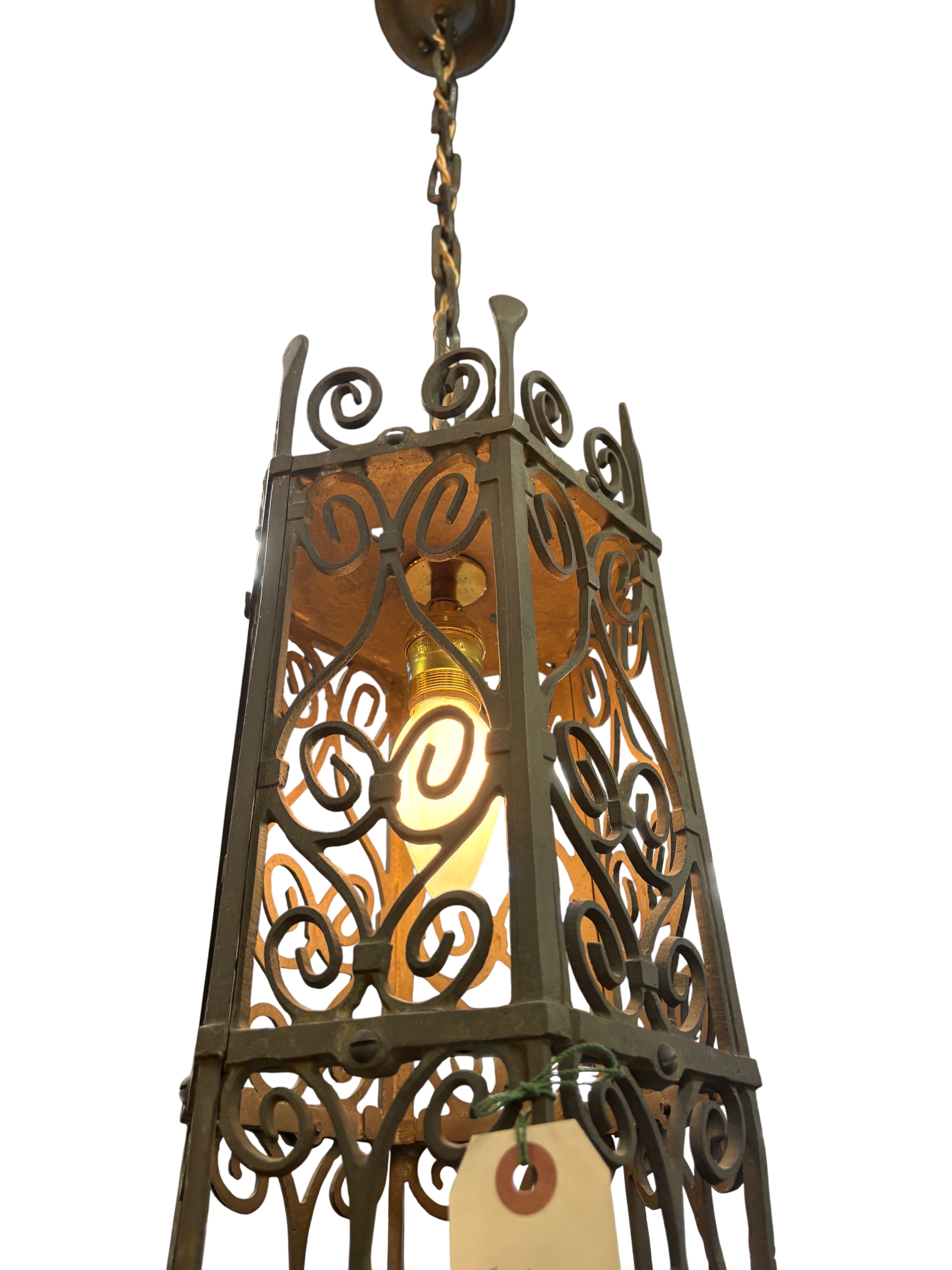 Decorative hanging light fixture with intricate designs in a rustic setting.
