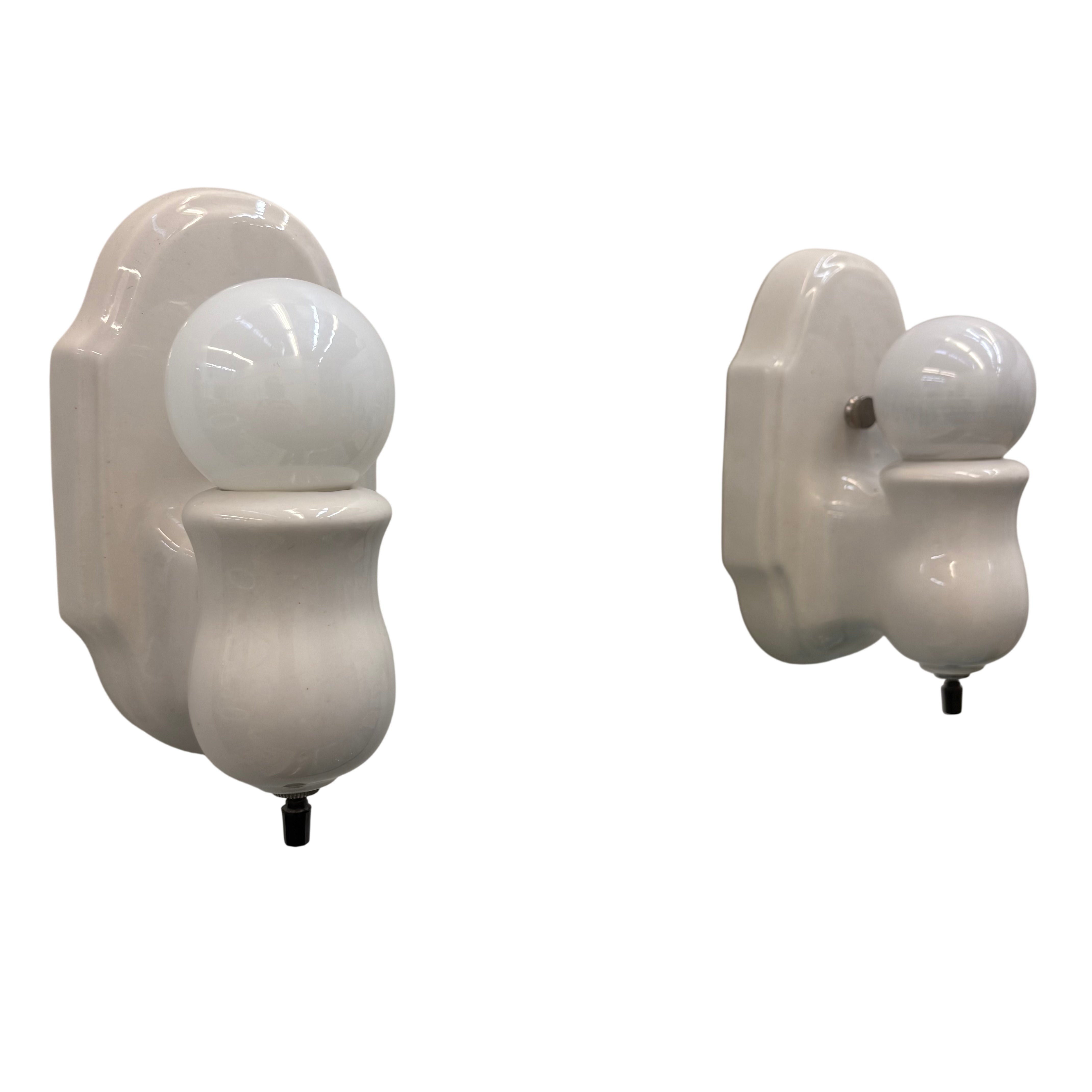 Two white wall sconces with spherical lights on a white background