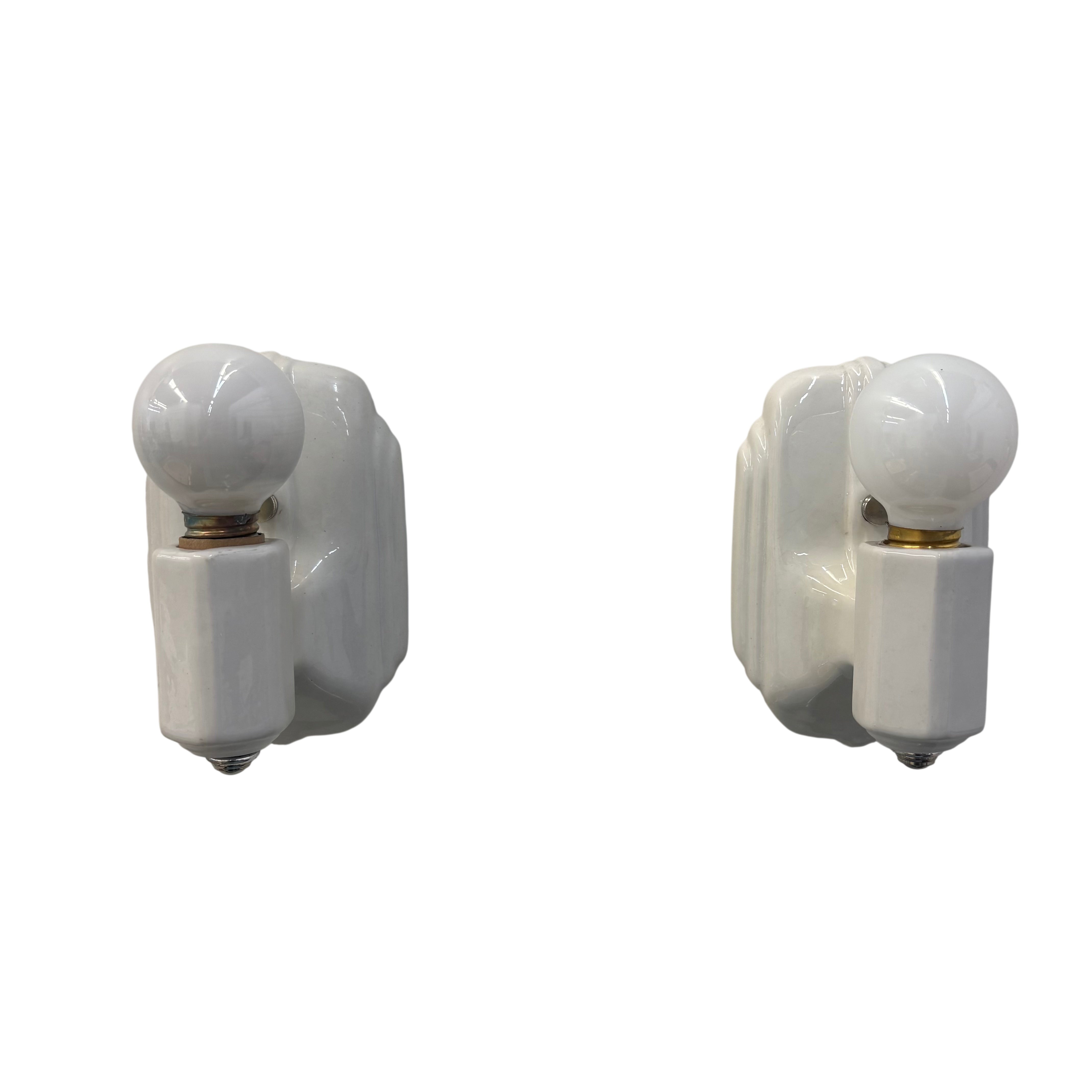 two white porcelain sconces with white light bulbs on a white background